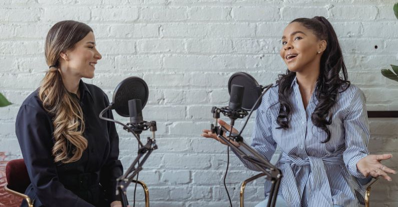 Hosting - Smiling African American female guest gesticulating while having interview with journalist sitting near mic